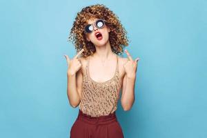 mulher encaracolado cabelo vermelho lábios mostra dedos em estúdio modelo face foto