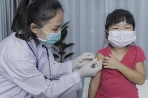 ásia médico injeção vacina para protegendo vírus covid-19 para uma menina vestem médico máscara, pessoas estão meninas estão vacinado contra gripe cada ano. foto