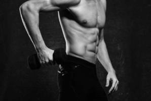 homem com uma bombeado tronco músculos halteres exercício Academia foto