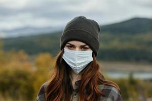 retrato do uma lindo viajante dentro uma médico mascarar ao ar livre dentro a outono floresta foto