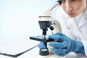 fêmea médico dentro médico mascarar microscópio tecnologia pesquisa foto