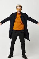 uma loiro homem dentro uma Preto casaco e calça laranja suéter tendência do a estação foto