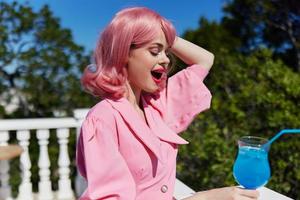 Deleitado jovem menina dentro Rosa vestir ao ar livre com coquetel feliz fêmea relaxante foto