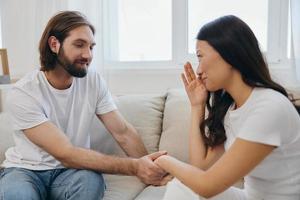 a ásia mulher é triste e chorando com dela masculino amigo às lar. estresse e mal entendido dentro uma relação entre dois pessoas e apoiando cada outros mental e emocional bem estar foto