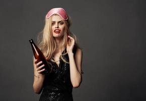indignado mulher com uma garrafa do Cerveja e uma Rosa mascarar em a cabeça do uma Loiras modelo foto
