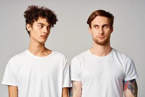 dois homens dentro branco Camisetas estão em pé Próximo para amizade emoções foto