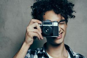 bonito cara com uma Câmera perto dele face e encaracolado cabelo xadrez camisa passatempo fotógrafo foto