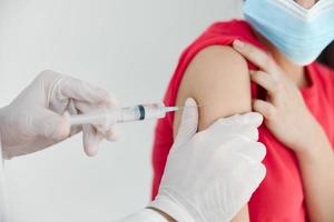 médico dentro médico luvas faz a injeção dentro a pacientes ombro cobiçado vacinação foto