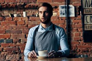 masculino garçom avental serviço café copo tijolo parede foto