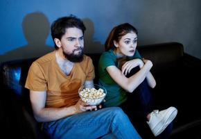 emocional mulher e homem em a sofá com Pipoca assistindo televisão foto