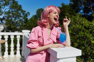 retrato do lindo mulher dentro Rosa vestir ao ar livre com coquetel verão dia foto