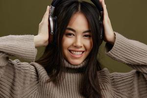 jovem mulher dentro uma suéter ouvindo para música com fones de ouvido Diversão verde fundo foto