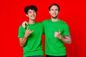 dois amigos dentro verde Camisetas abraços Diversão vermelho fundo foto