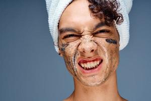 alegre cara com nu ombros com uma toalha em dele cabeça, uma Preto mascarar em dele face foto