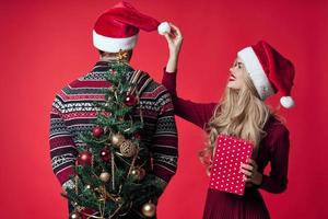 alegre jovem casal dentro santa chapéus Natal árvore brinquedos decorações foto