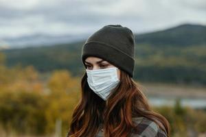 mulher dentro uma médico mascarar dentro a montanhas perto a outono floresta foto