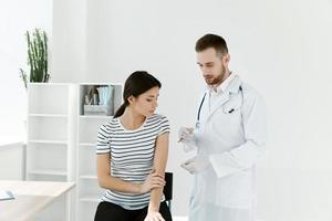 masculino médico dentro uma branco casaco dando a injeção para uma mulher dentro uma hospital cobiçado vacinação foto