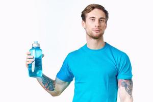 sexy atletas com uma garrafa do água e dentro uma azul camiseta em uma branco fundo beber foto