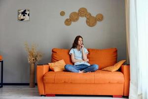 retrato do uma mulher em a sofá descansar Diversão conforto apartamentos foto