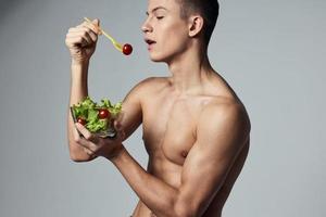 Esportes cara com uma nu tronco saudável comendo vegetal salada energia exercite-se foto