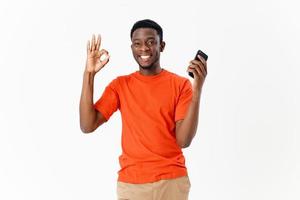 alegre africano americano com telefone dentro mãos respeitoso gesto com mão comunicação luz fundo foto