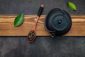 bule de chá preto de ferro fundido com chá de ervas em um fundo de pedra escura foto