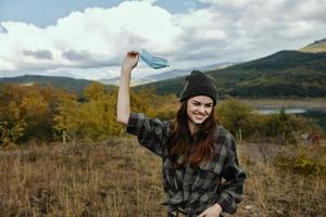 feliz mulher detém uma médico mascarar dentro dela mão em natureza dentro a floresta e montanhas dentro a fundo foto