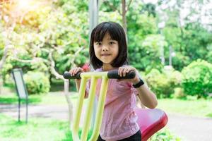 alegre criança menina jogando em Parque infantil dentro a parque. saudável verão atividade para crianças. foto