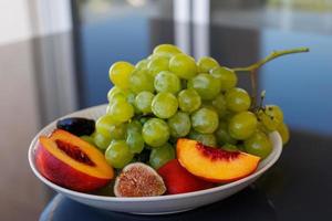 pratos com saudável fruta, verde uvas, pêssego, FIG foto