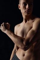 homem com bombeado acima braço músculos em uma Preto fundo fisiculturista ginástica atleta foto