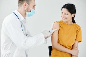 médico fitas a injeção em a ombro do uma feliz paciente com adesivo fita cobiçado foto
