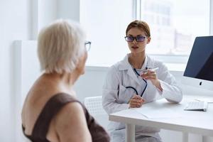 idosos mulher com óculos consulta com uma médico saúde diagnóstico foto