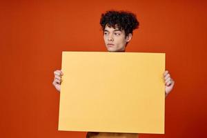 cara com encaracolado cabelo amarelo poster dentro mãos estúdio publicidade foto