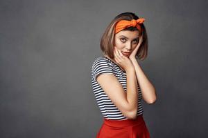 bonita elegante mulher com laranja arco de cabelo vermelho saia posando foto