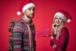 jovem casal Natal decorações feriado posando vermelho fundo foto