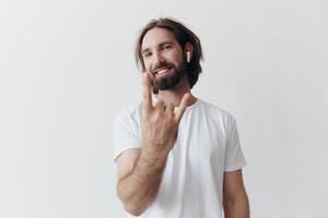 à moda homem dentro uma branco camiseta com sem fio fones de ouvido dentro dele orelhas tendo Diversão ouvindo para música sorrir em uma branco fundo estilo de vida foto