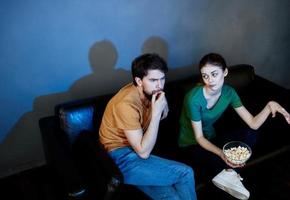 uma homem e uma mulher estão assistindo uma filme dentro a cinema em a sofá dentro de casa foto