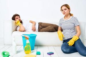 jovem casal às casa perto sofá lavando suprimentos limpeza estilo de vida foto