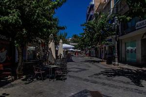 eu urbano panorama do uma espanhol rua dentro Benidorm com uma cafeteria e mesas em a calçada sem pessoas foto
