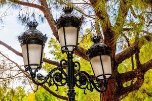 Antiguidade metal Preto lanterna dentro a cidade contra a pano de fundo do verde árvores foto