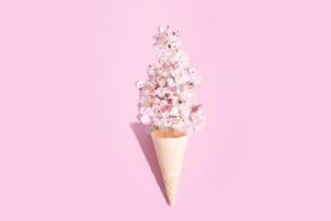 uma waffle cone com delicado cereja Flor pétalas em uma Rosa fundo. Primavera criativo foto