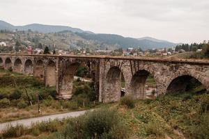 velho estrada de ferro viaduto dentro a montanha recorrer Vila do vorokhta. Ucrânia, Cárpatos. foto