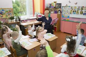 primário escola professor e crianças às seus mesas. foto