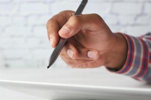 mão com caneta escrevendo no tablet digital foto