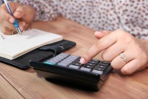 mão de uma mulher usando calculadora na mesa do escritório foto