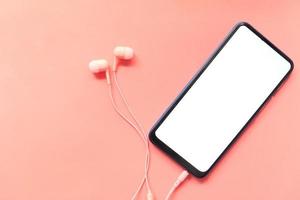 telefone inteligente com tela vazia e fones de ouvido em fundo rosa foto