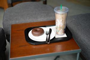donut de chocolate servido com um copo de café pessoal foto