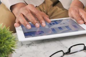 a mão do homem trabalhando em um tablet digital na mesa do escritório foto