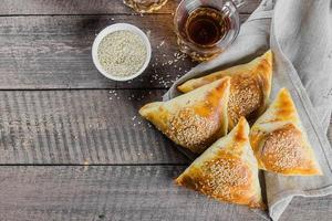 delicioso samosas samsa com carne, vidro do chá em de madeira mesa. leste ásia prato. Ramadã Comida foto