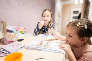 dois fofa pequeno irmãs pintura às lar. foto